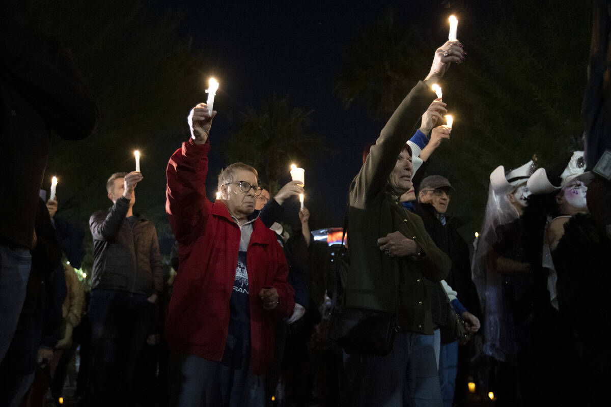 Members of the queer community and allies hold their candles to the sky during a vigil at the L ...
