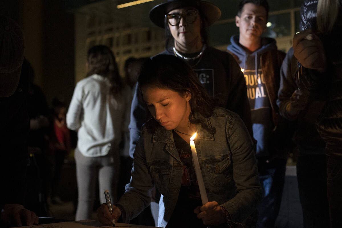 Cian Coey, of Las Vegas, writes a note on a canvas during a vigil at the LGBTQ Center of Southe ...