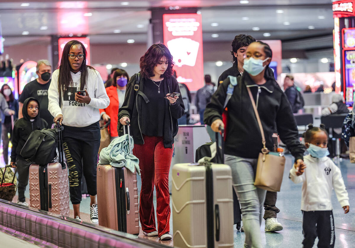 Travelers walk through the baggage claim at Harry Reid International Airport in Las Vegas, Wedn ...