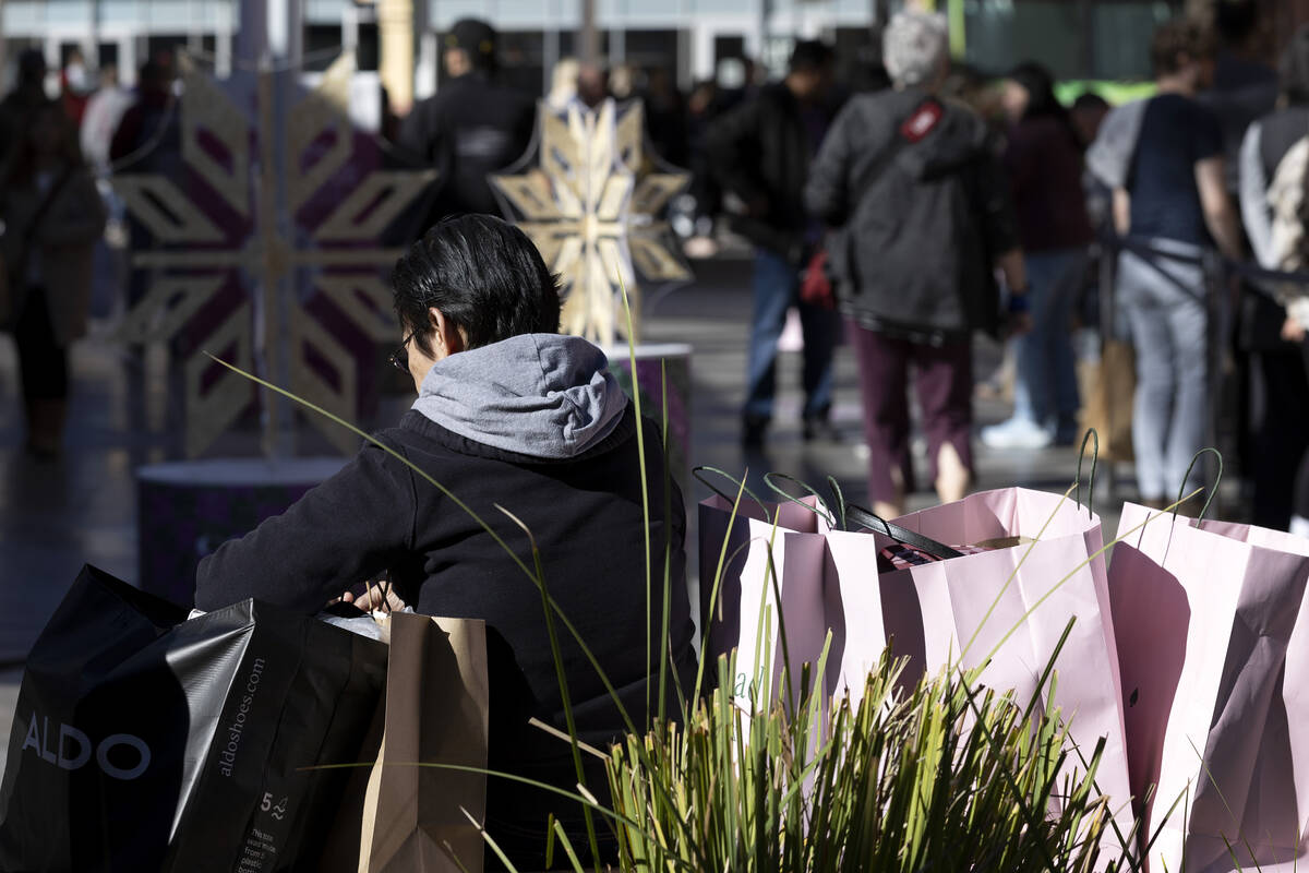 A shopper takes a break with their haul during Black Friday sales at Las Vegas North Premium Ou ...