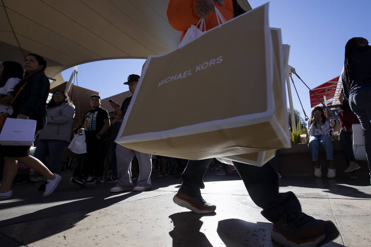 A shopper carries purchases from Michael Kors during Black Friday sales at Las Vegas North Prem ...