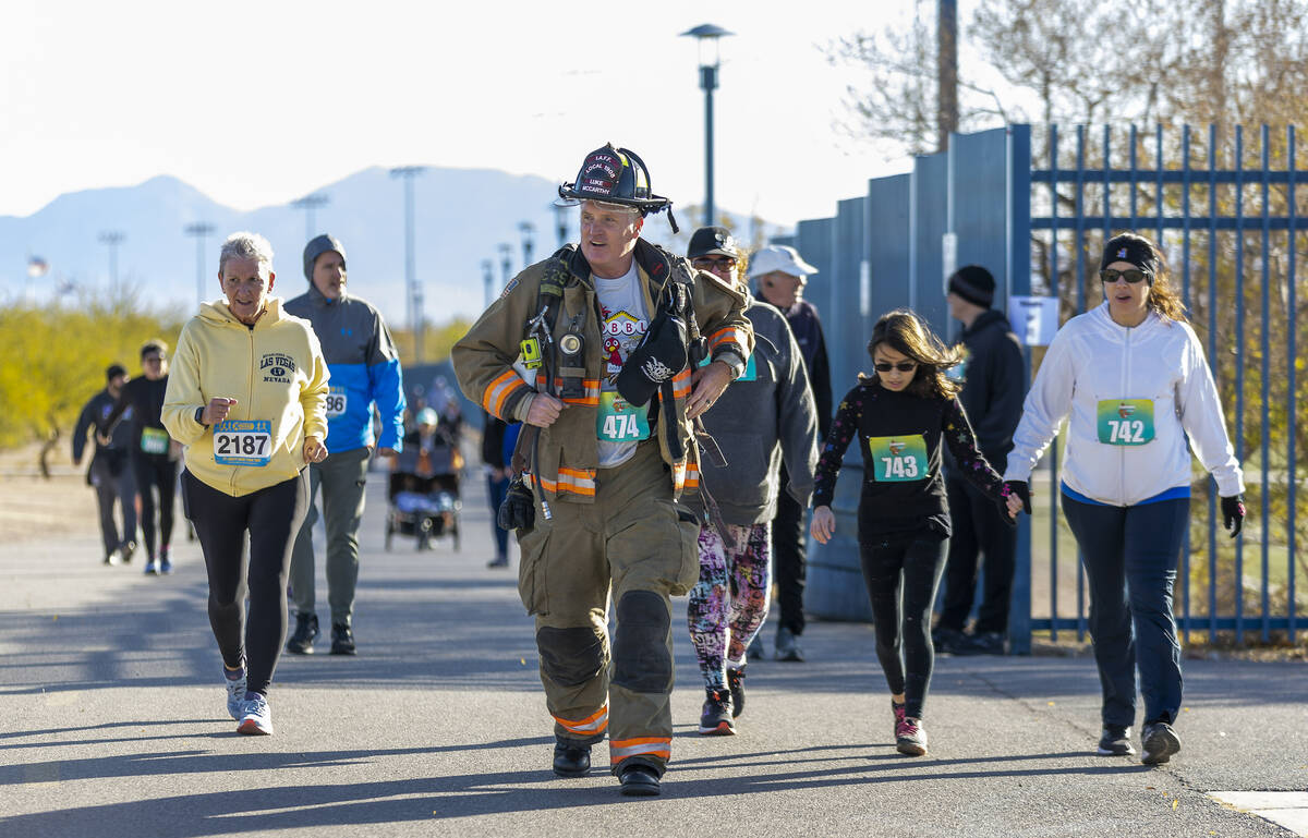 Luke McCarthy with Clark County Fire runs with full firefighter turnout gear to honor his colle ...
