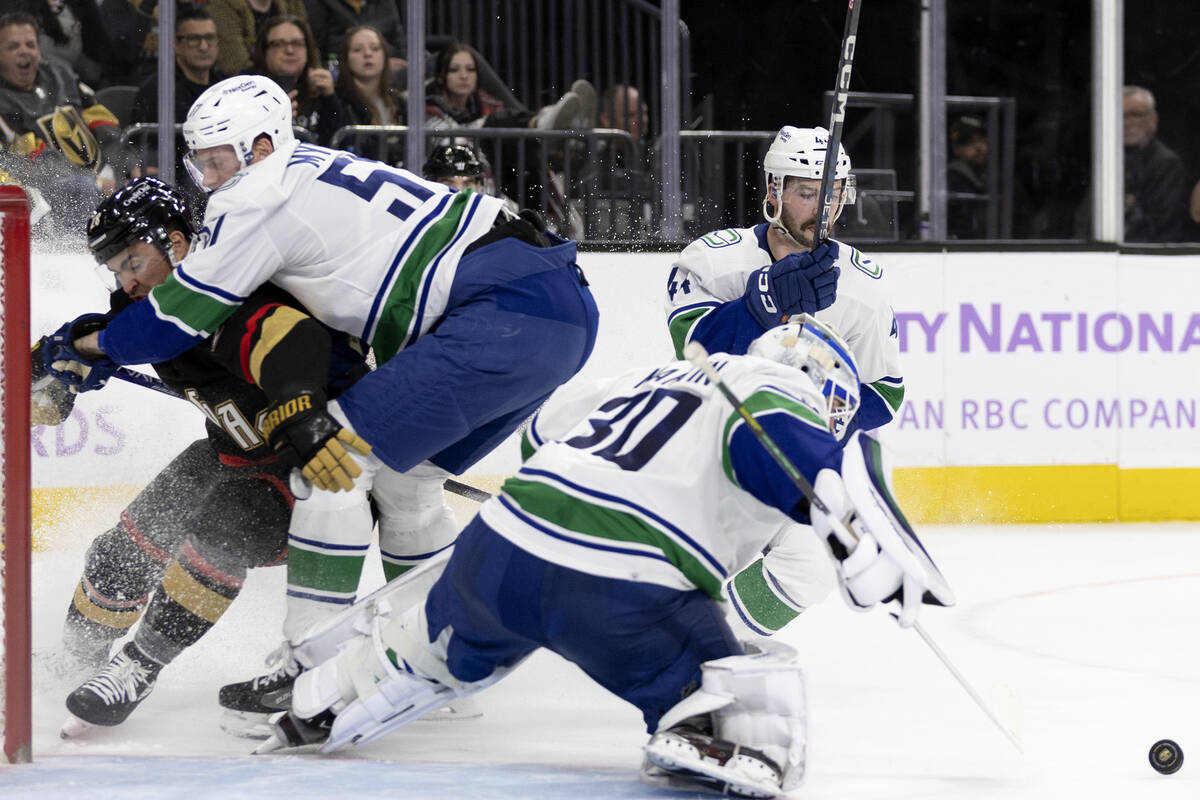 Golden Knights left wing William Carrier (28) collides with Canucks defenseman Tyler Myers (57) ...