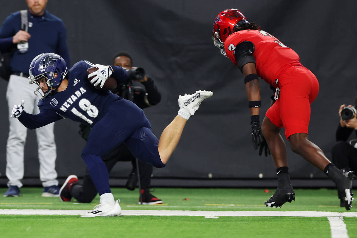 Nevada Wolf Pack wide receiver Spencer Curtis (18) gets pushed out of bounds by UNLV Rebels def ...