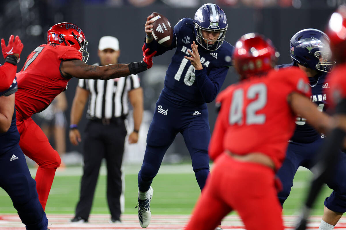 Nevada Wolf Pack quarterback Nate Cox (16) gets sacked by UNLV Rebels defensive lineman Adam Pl ...