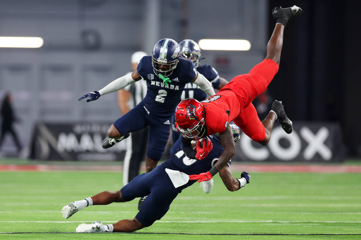 UNLV Rebels wide receiver Senika McKie (0) is tackled by Nevada Wolf Pack defensive back Jaden ...