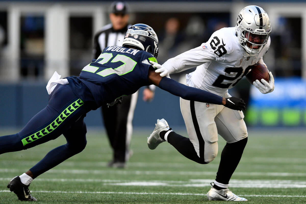 Las Vegas Raiders running back Josh Jacobs (28) runs around Seattle Seahawks cornerback Tariq W ...