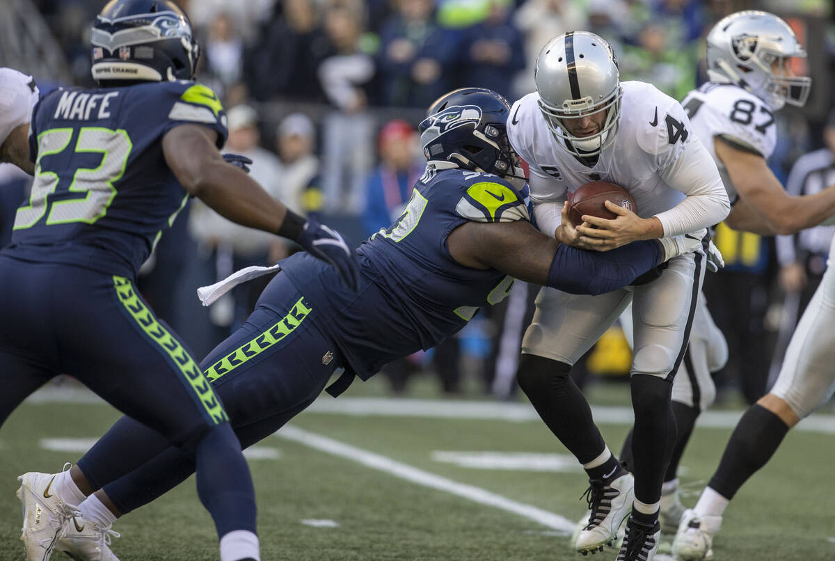 Raiders quarterback Derek Carr (4) is sacked by Seattle Seahawks defensive tackle Bryan Mone (9 ...