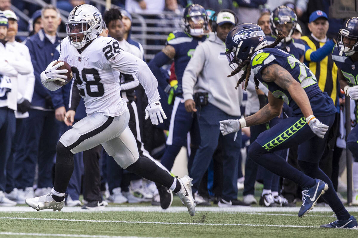 Raiders running back Josh Jacobs (28) runs past Seattle Seahawks safety Ryan Neal (26) to the e ...