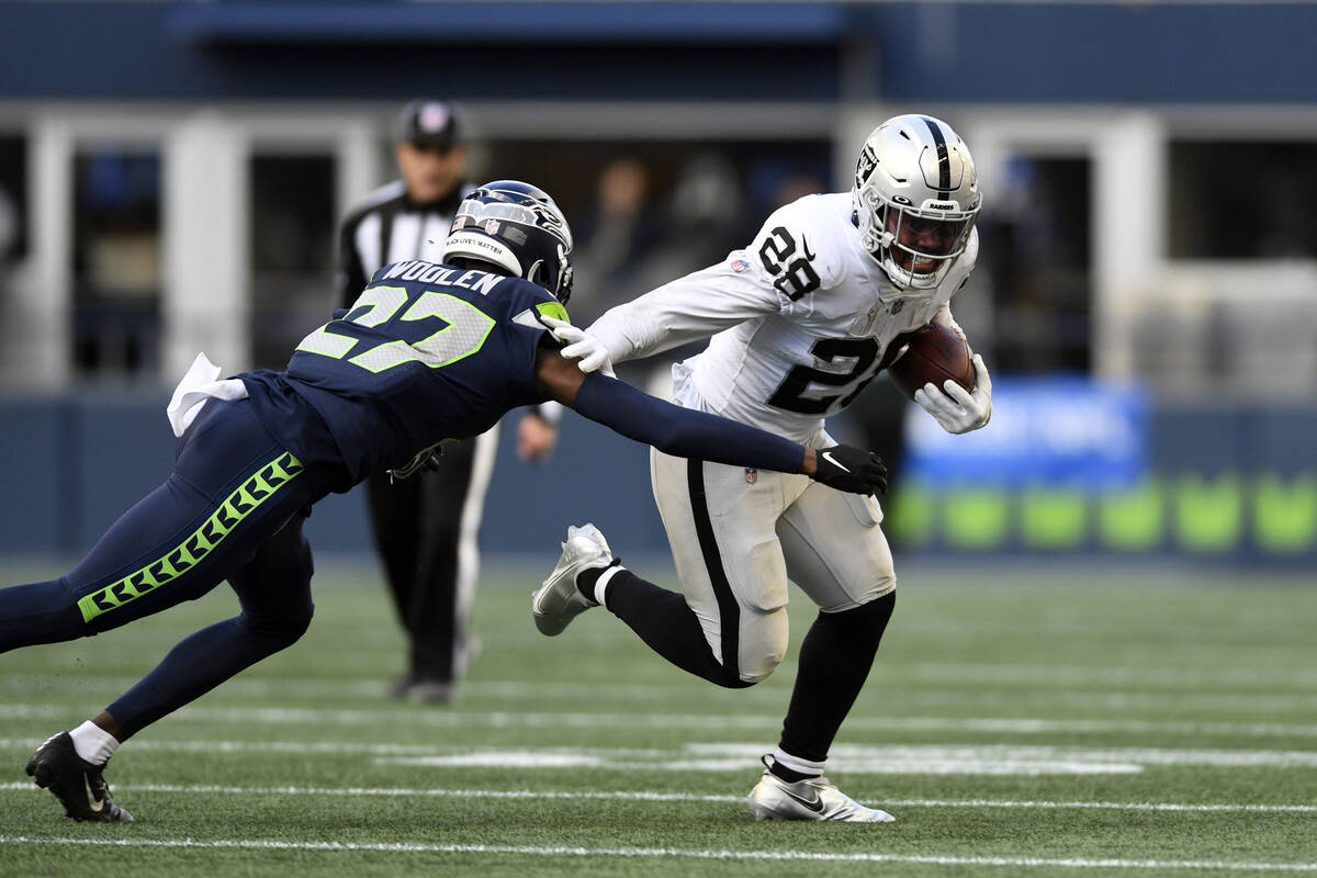 Las Vegas Raiders running back Josh Jacobs (28) runs around Seattle Seahawks cornerback Tariq W ...