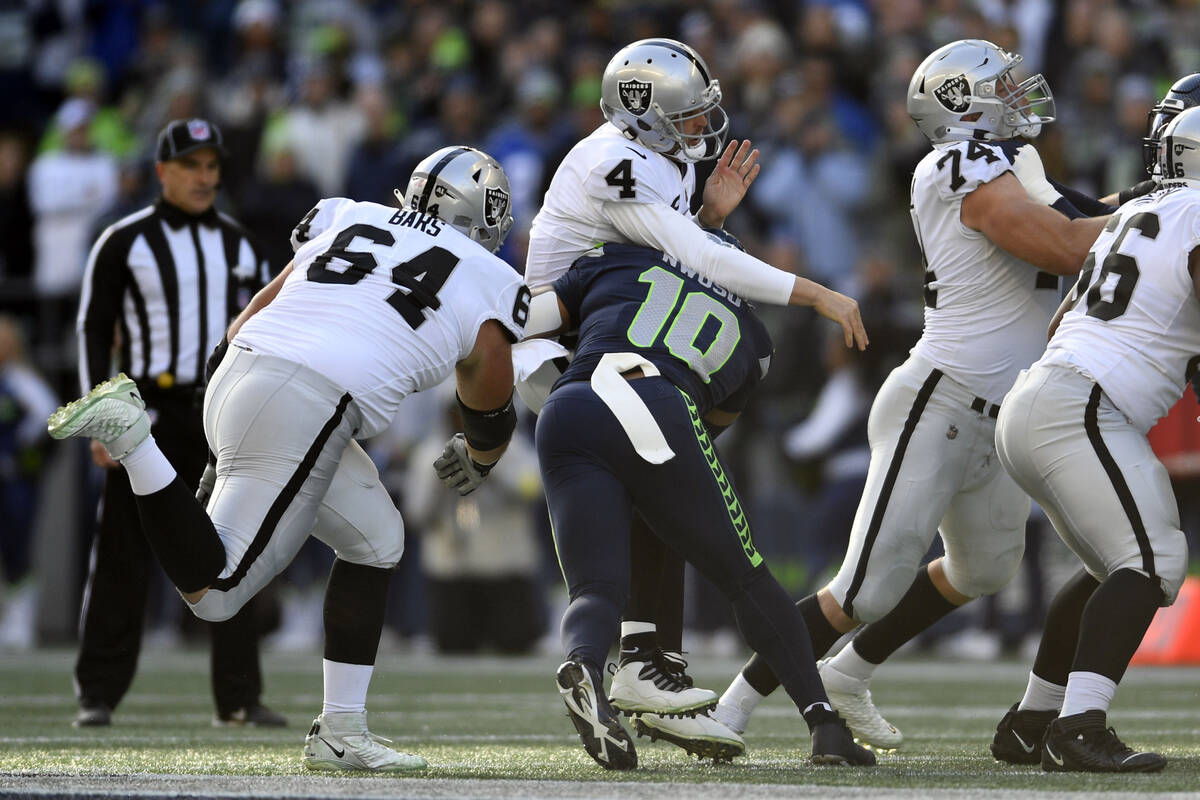 Las Vegas Raiders quarterback Derek Carr (4) is hit by Seattle Seahawks linebacker Uchenna Nwos ...