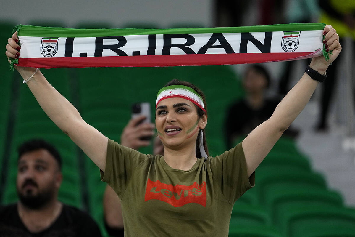 A fan holds up a scarf prior the start of the World Cup group B soccer match between Iran and t ...