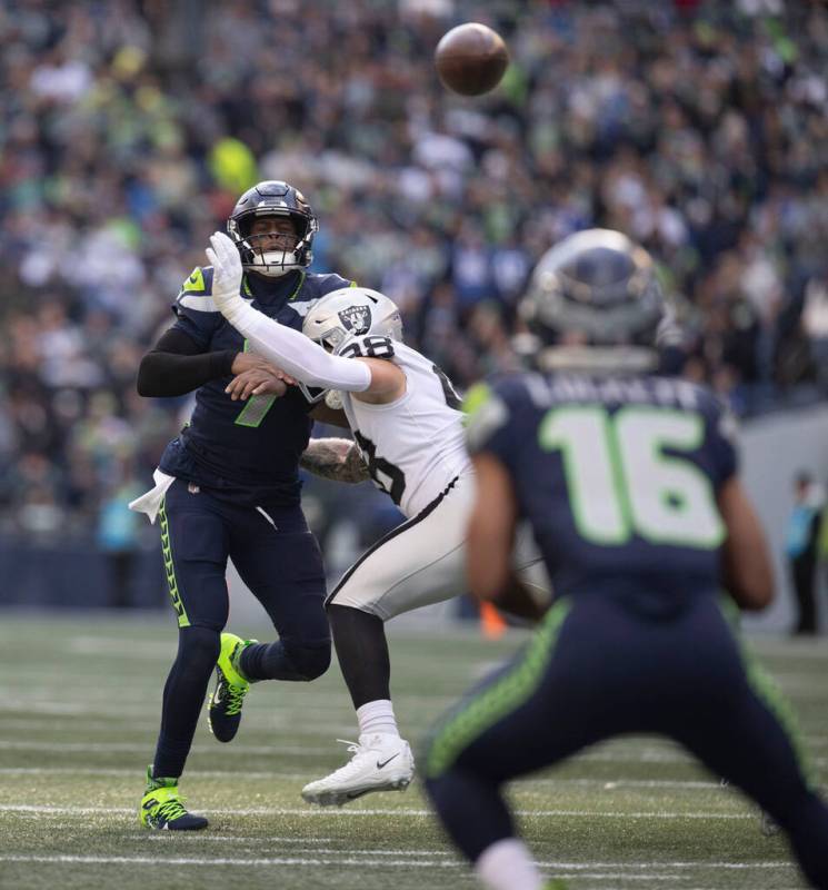 Raiders defensive end Maxx Crosby (98) hits Seattle Seahawks quarterback Geno Smith (7) as he t ...