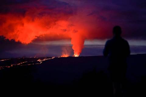 A man looks on as lava erupts from Hawaii's Mauna Loa volcano Wednesday, Nov. 30, 2022, near Hi ...