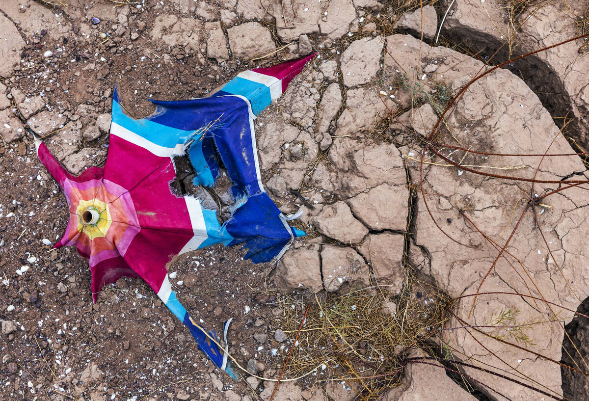 An old umbrella breaks down remaining in dried mud as the water level continues to recede at th ...