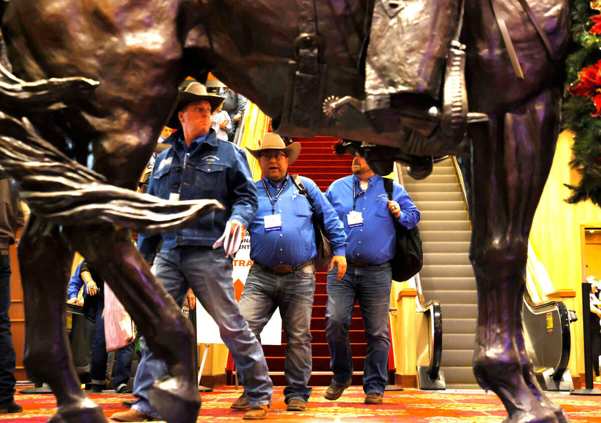 Cowboys walk past Benny Binion's statue, the man who brought the National Finals Rodeo to Las V ...