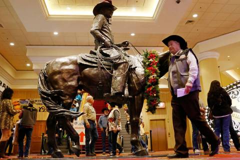 Atendees walk past Benny Binion's statue, the man who brought the National Finals Rodeo to Las ...