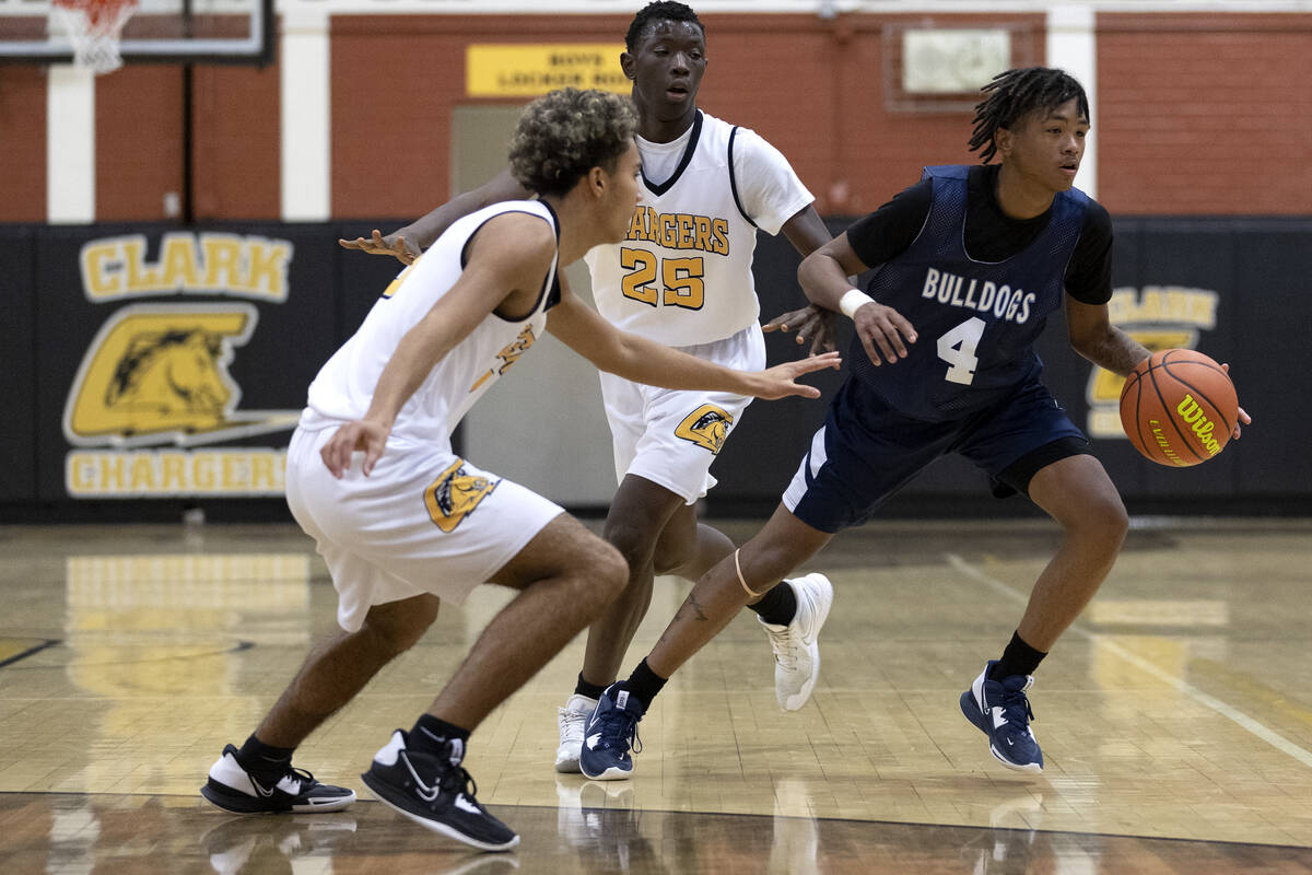 Centennial’s Levi Sweeney (4) dribbles around Clark’s Traci Hutchins, left, and O ...
