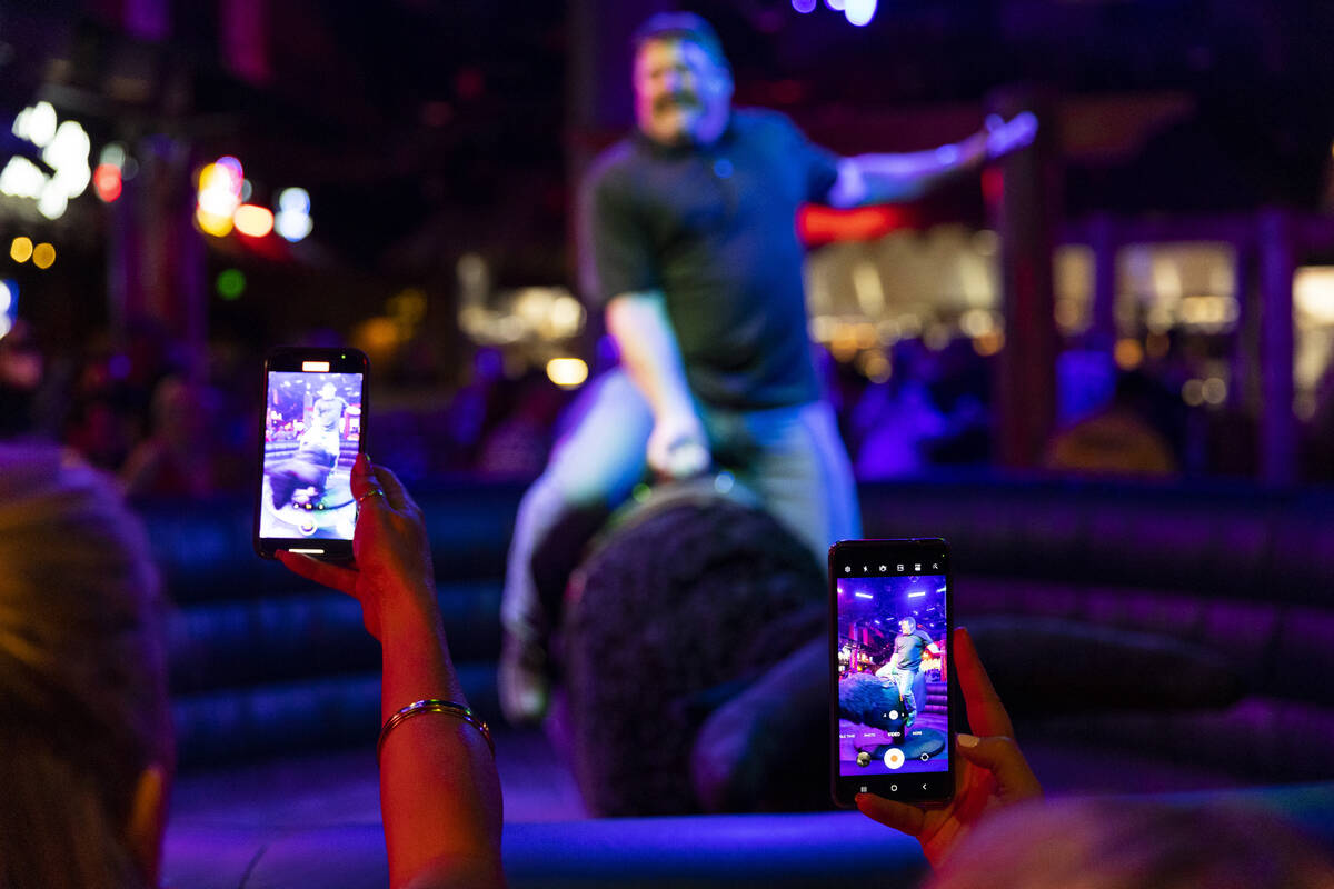 People watch a person ride a mechanical bull at Gilley's Saloon inside of Treasure Island hotel ...