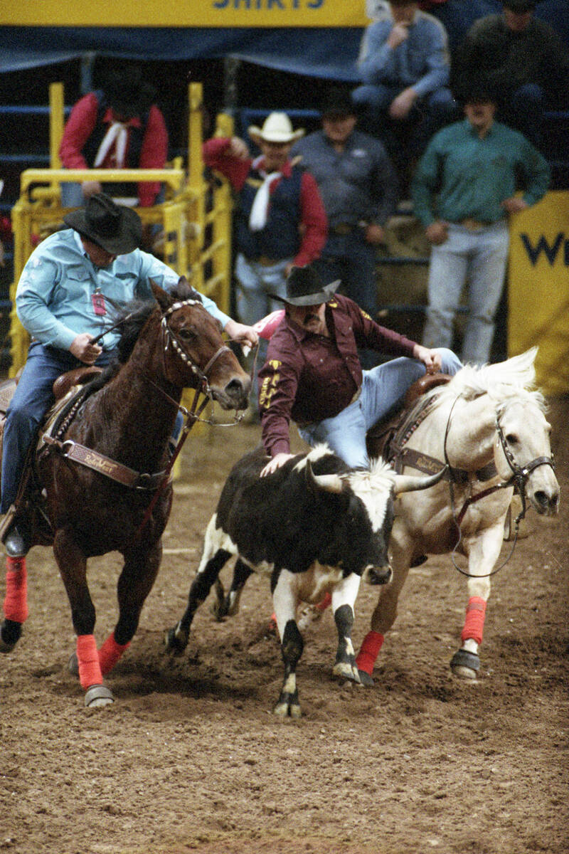 Two men compete in a team roping competition on Canada night in the National Finals Rodeo at th ...