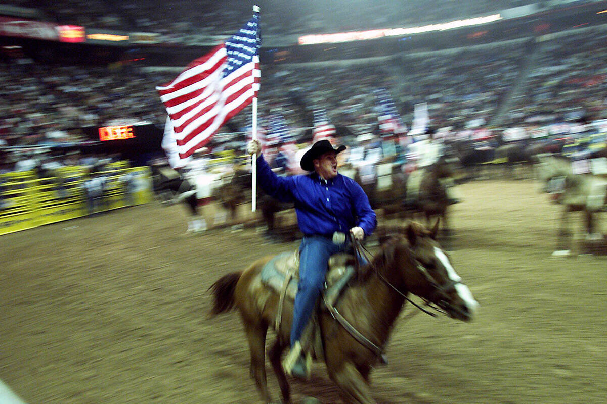 Steer wrestler Brock Andrus of St. George, Utah, carries an American flag with 117 other contes ...