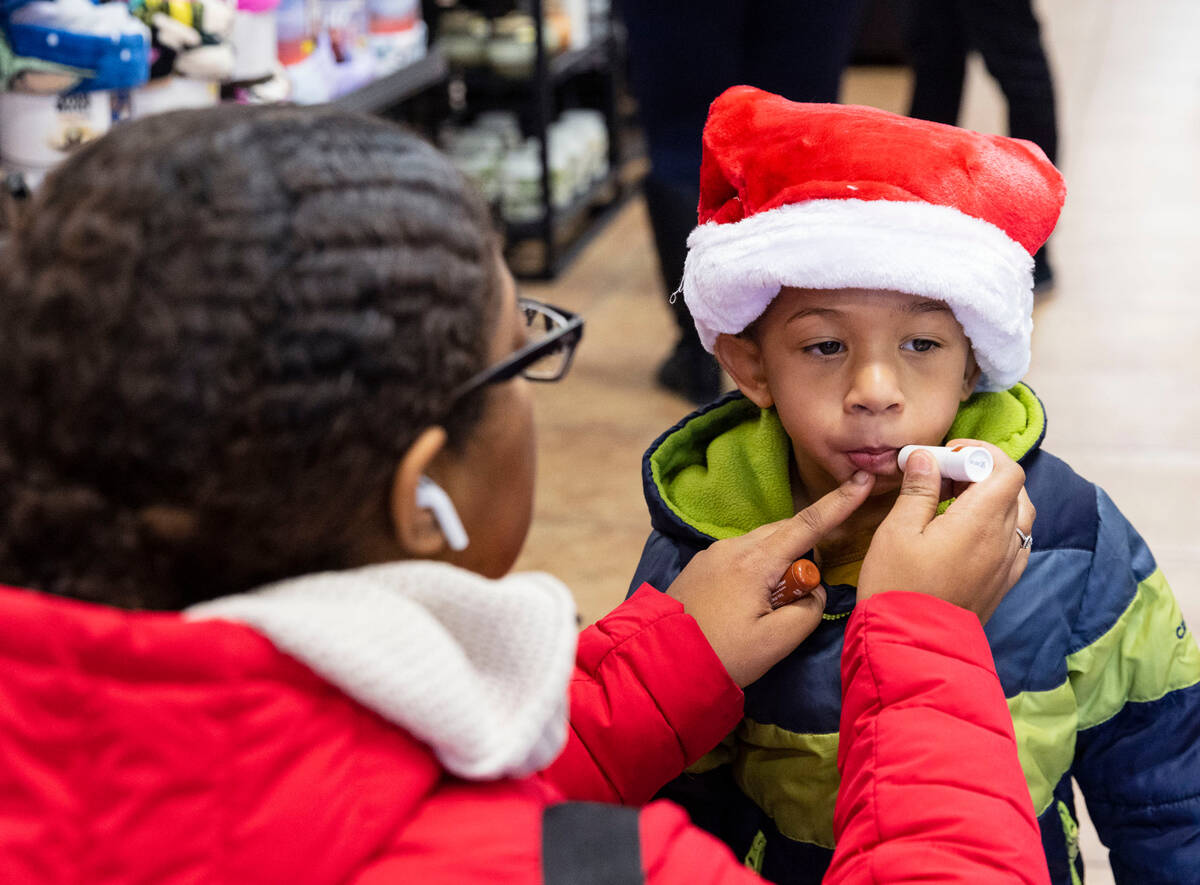 Ashley Tineo applies chapstick on her grandson Asa McKenzie, 3, as they wait for Santa Claus to ...