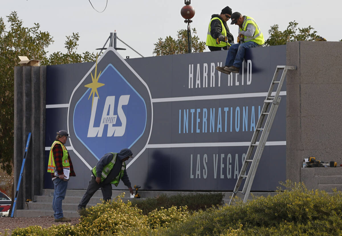 Workers change signage from McCarran International Airport to Harry Reid at Koval Lane and Trop ...