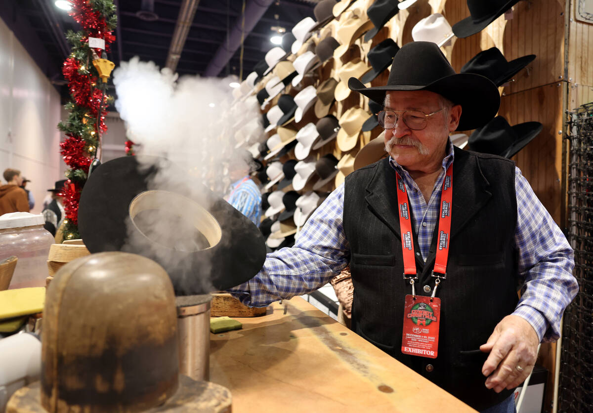 Rick Bishop, right, co-owner of Western Tradition hats and hat accessories, uses steam to shape ...