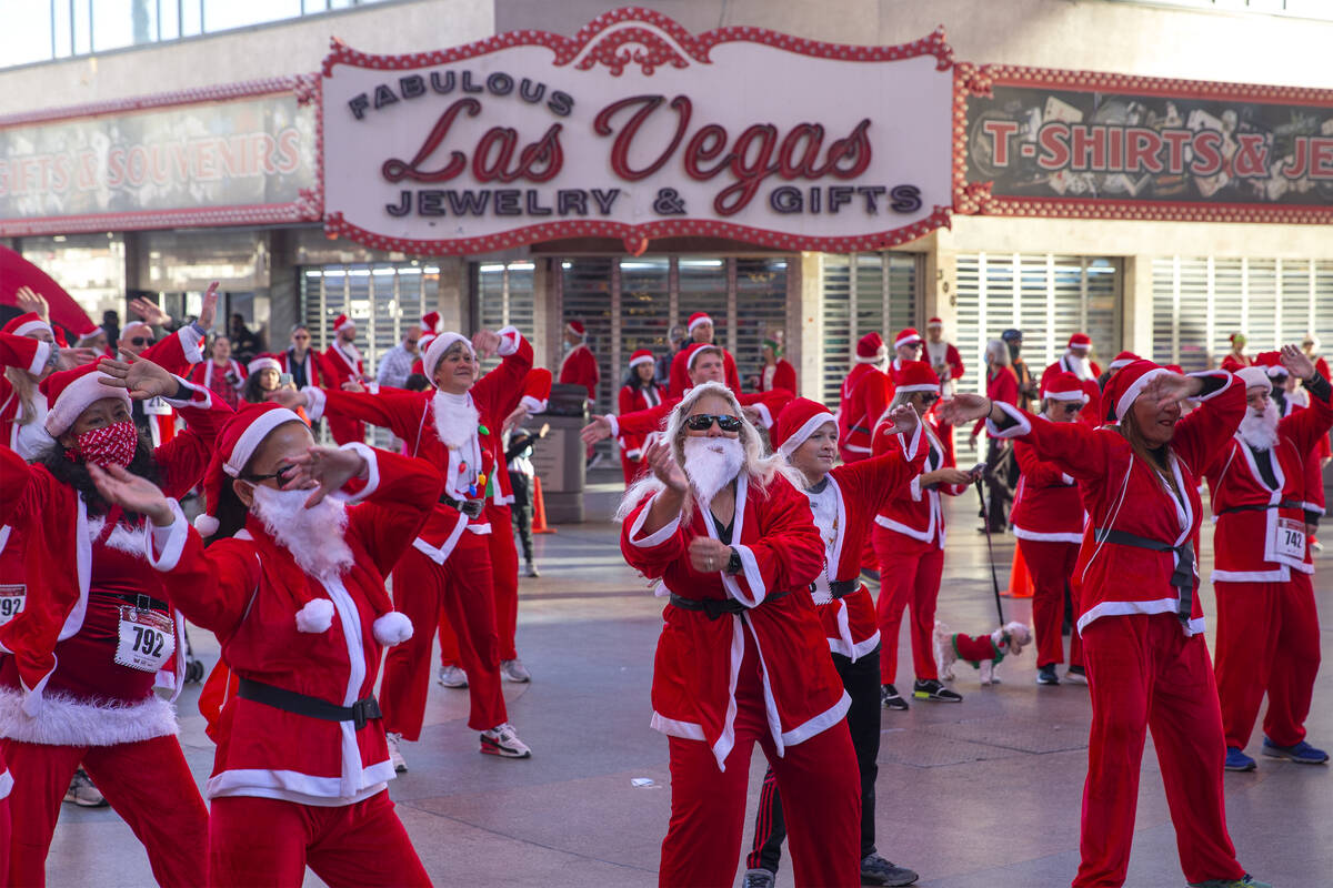 Santas warm up at Fremont Street Experience during The Las Vegas Great Santa Run on Saturday, D ...