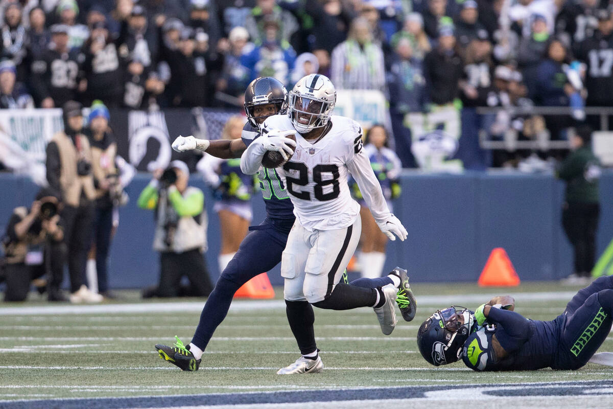 Raiders running back Josh Jacobs (28) looks for room to run against Seattle Seahawks cornerback ...