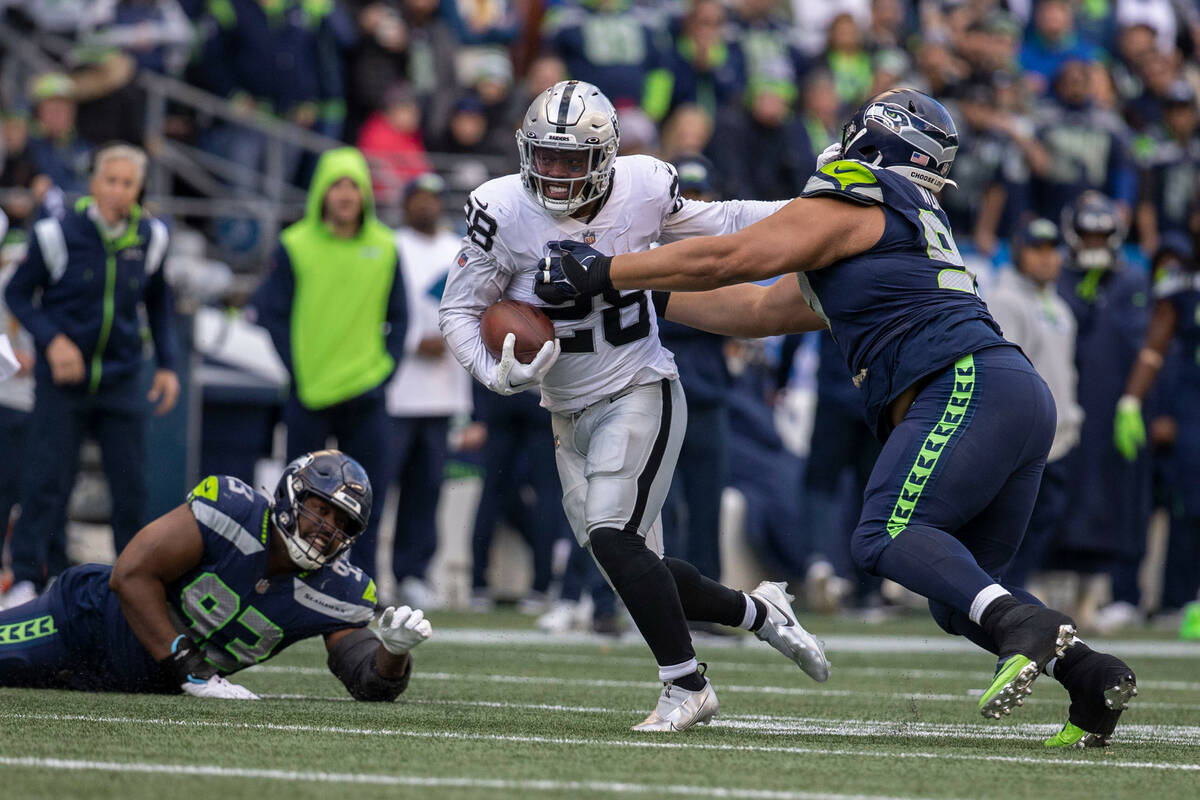 Raiders running back Josh Jacobs (28) stiff arms Seattle Seahawks defensive tackle Al Woods (99 ...