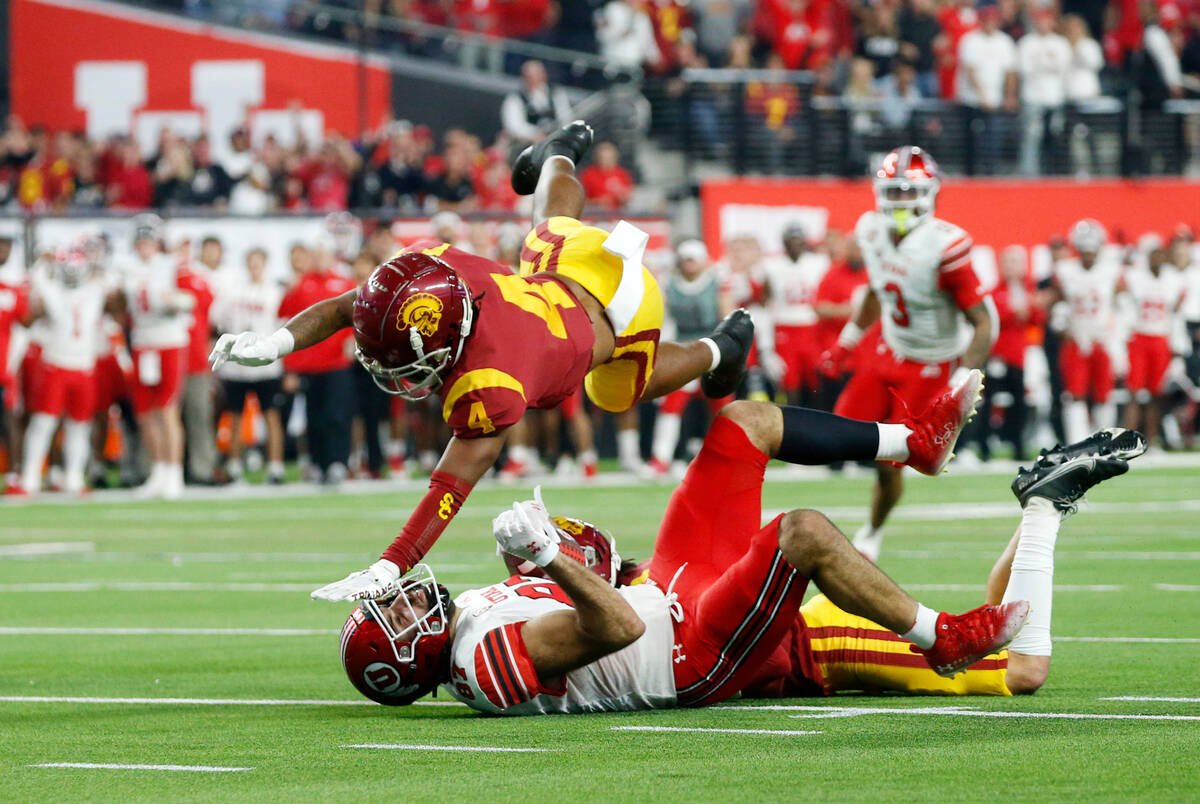 Southern California defensive back Max Williams (4) flies over Utah tight end Thomas Yassmin (8 ...