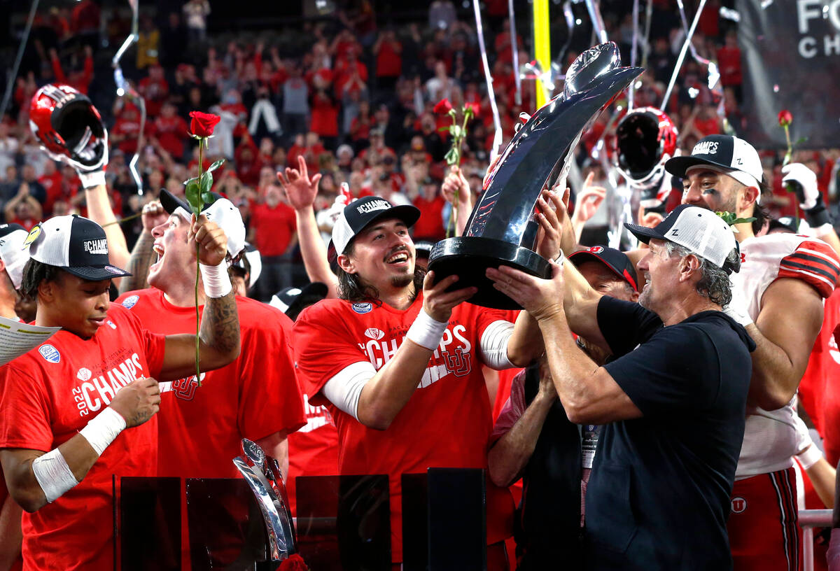 Utah coach Kyle Whittingham, right, hands the trophy to quarterback Cameron Rising, center, aft ...