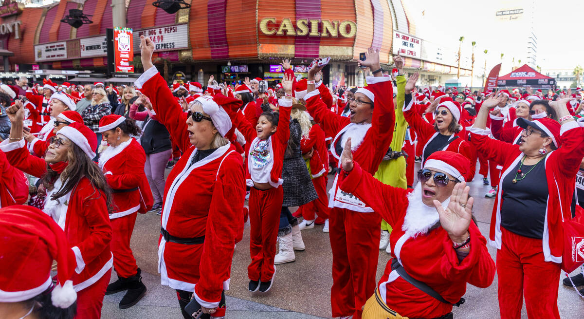 Participants clad in Santa outfits sing and dance during the pre-race entertainment at the Frem ...