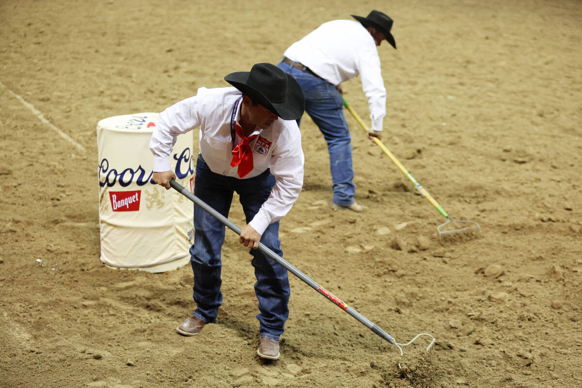 Crew members even out the dirt during the barrel racing event in the 64th Wrangler National Fin ...