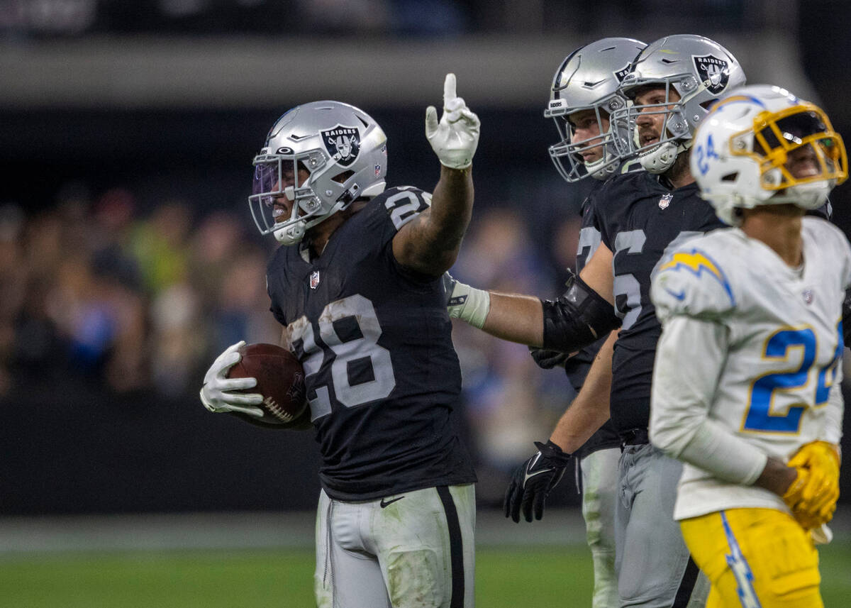 Raiders running back Josh Jacobs (28) signals for a first down with tight end Foster Moreau (87 ...