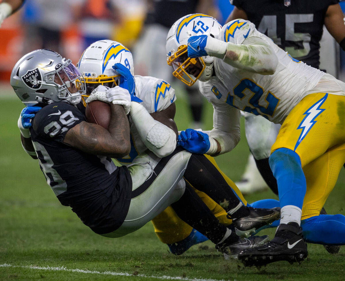 Raiders running back Josh Jacobs (28) is tackled by Los Angeles Chargers linebacker Khalil Mack ...