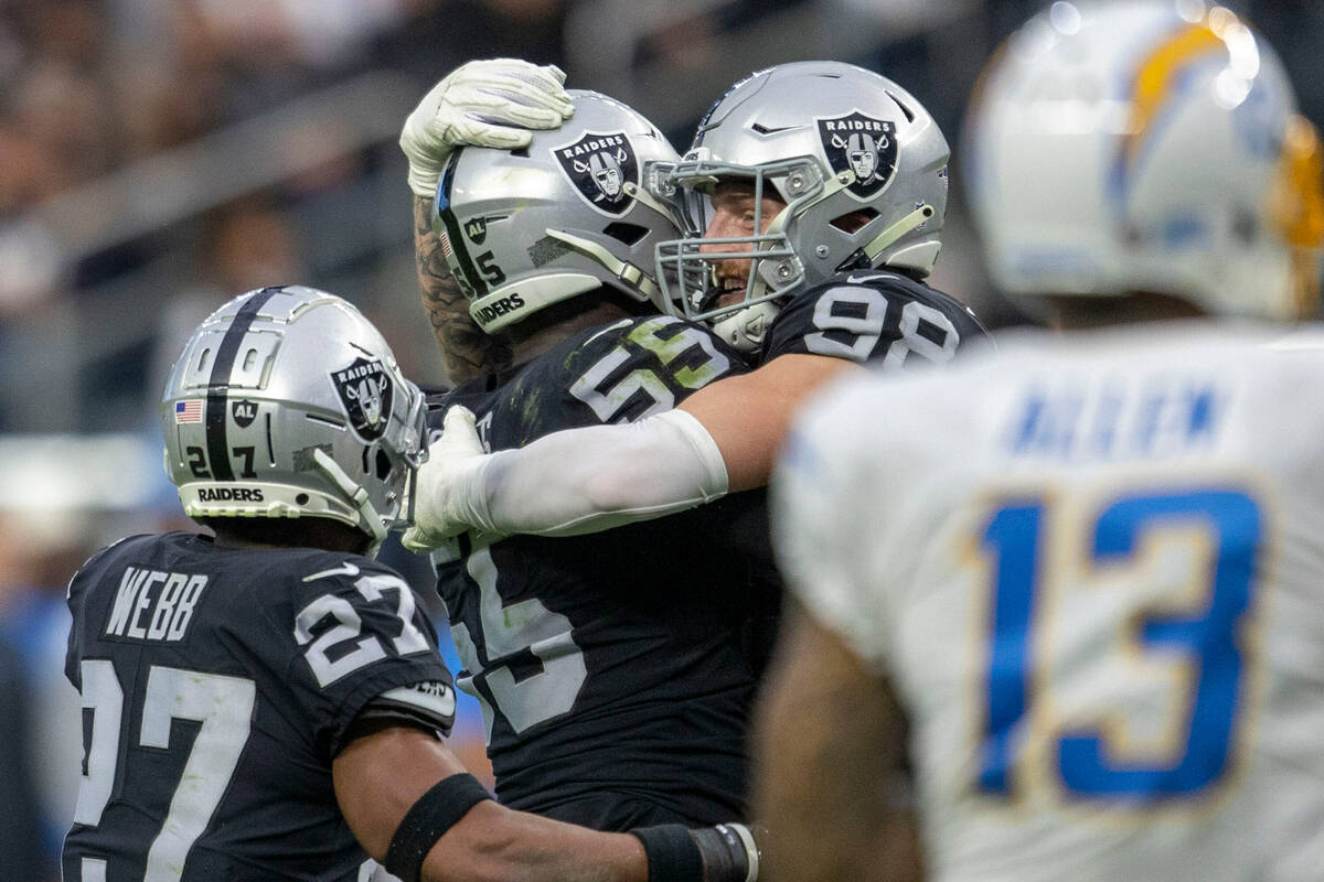 Raiders defensive end Chandler Jones (55) is embraced by Maxx Crosby (98) after securing a sac ...