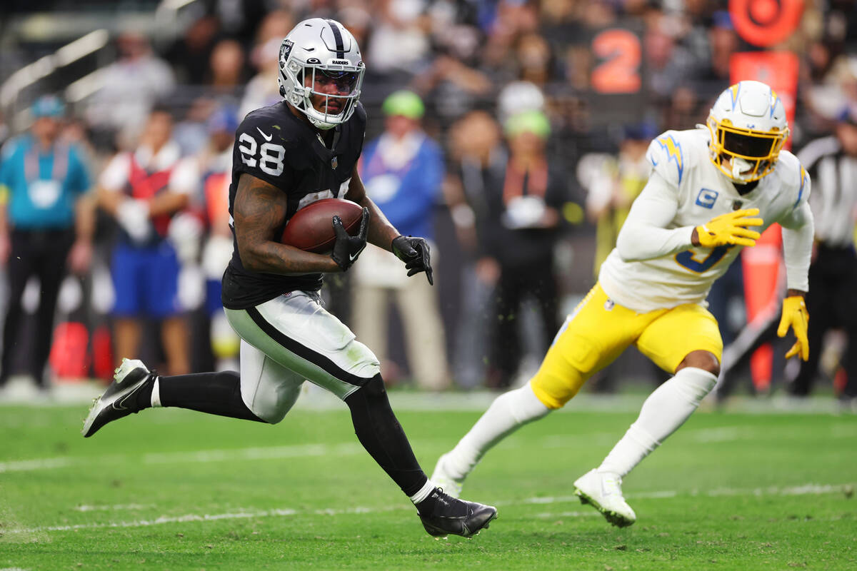 Raiders running back Josh Jacobs (28) runs for a touchdown as Los Angeles Chargers safety Derwi ...