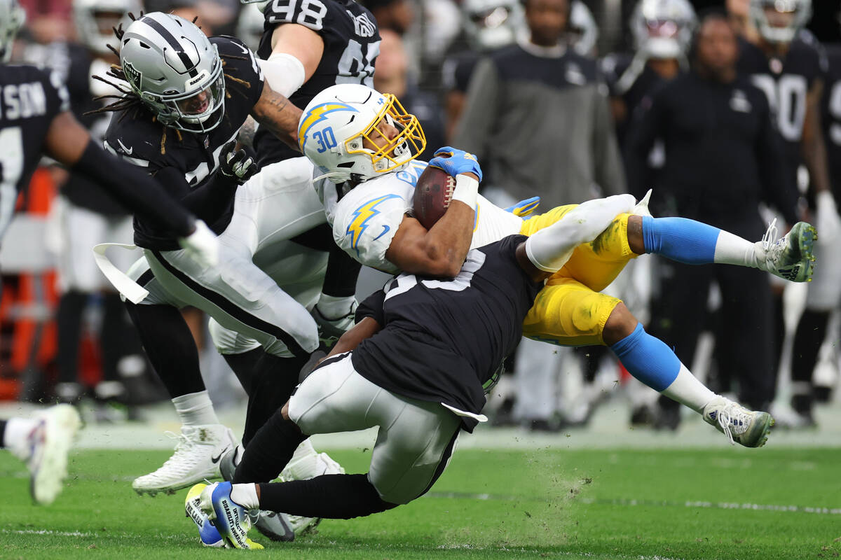 Raiders cornerback Nate Hobbs (39) tackles Los Angeles Chargers running back Austin Ekeler (30) ...