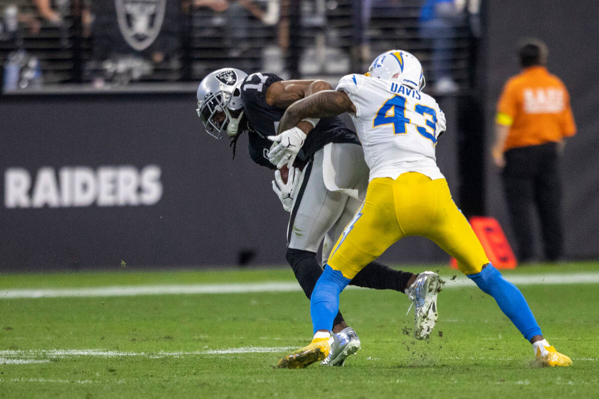 Raiders wide receiver Davante Adams (17) makes a catch with Los Angeles Chargers cornerback Mic ...