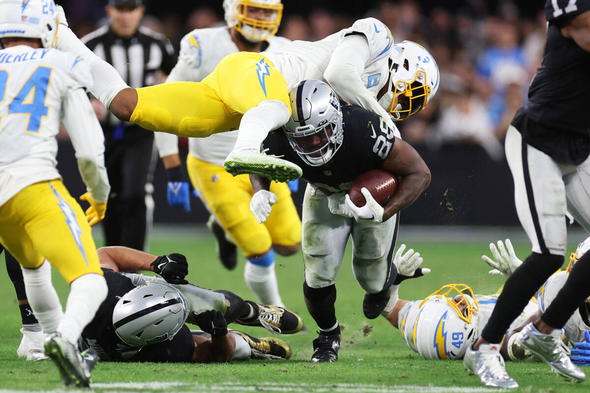 Raiders running back Josh Jacobs (28) is tackled by Los Angeles Chargers safety Derwin James Jr ...