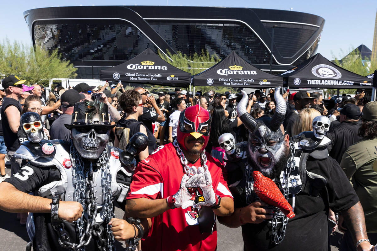 Raiders fans Carlos Aragon, left, and Willam Flores, right, pose for a photo with Arizona Cardi ...