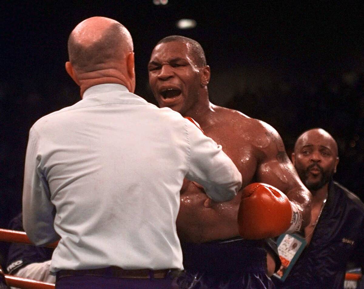 Referee Mills Lane, left, is verbally attacked by boxer Mike Tyson during his match against Eva ...