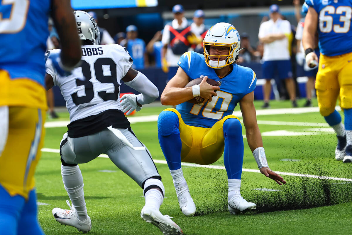 Los Angeles Chargers quarterback Justin Herbert (10) slides to the ground in front of Raiders c ...