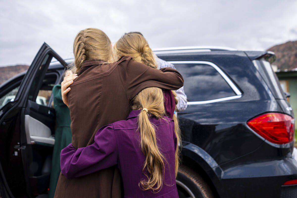 Three girls embrace before they are removed from the home of Samuel Bateman, following his arre ...