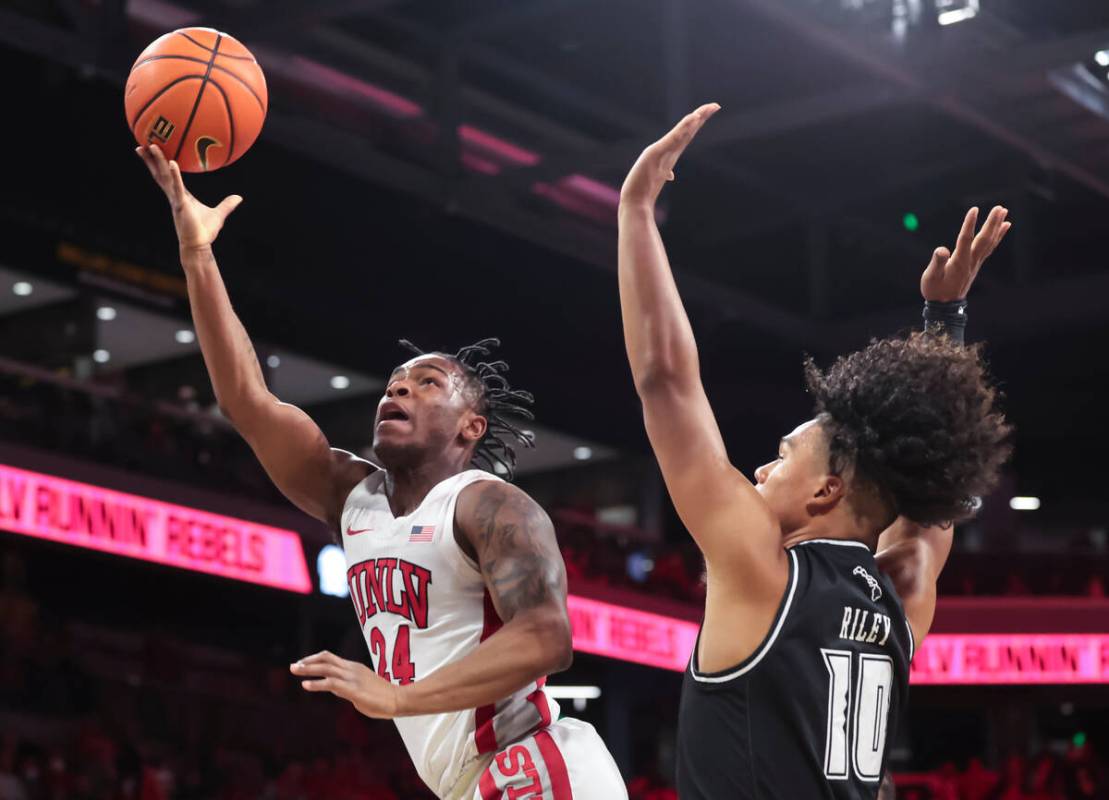 UNLV Rebels guard Jackie Johnson III (24) lays up the ball around Hawaii Warriors guard Beon Ri ...
