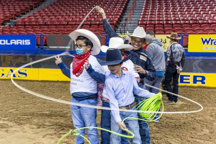 Participants Roman Chatfield, 8, left, and Jeremiah Brown, 8, center, have lassos twirled about ...