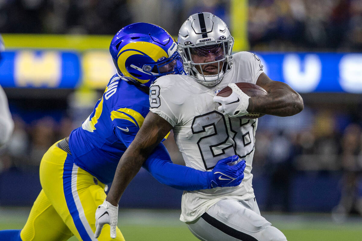 Raiders running back Josh Jacobs (28) rushes as Los Angeles Rams defensive tackle Marquise Cope ...
