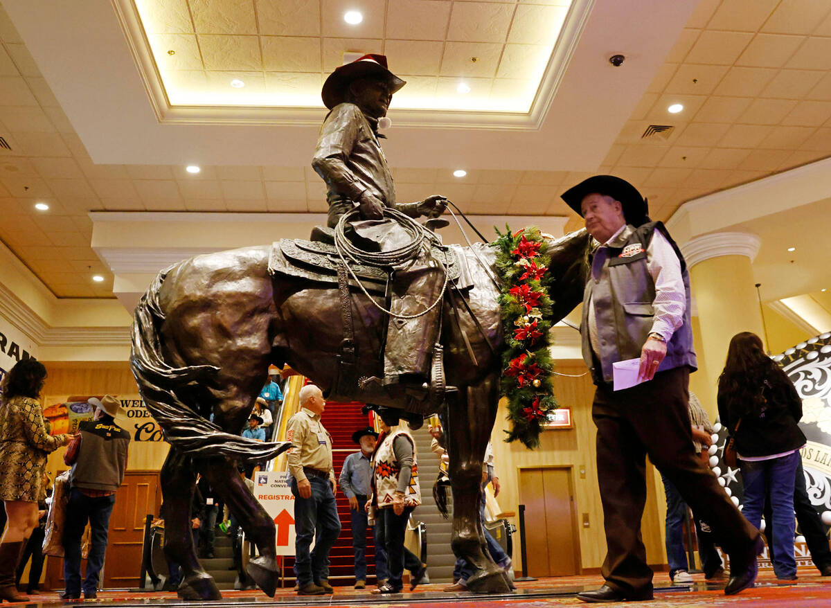 Atendees walk past Benny Binion's statue, the man who brought the National Finals Rodeo to Las ...